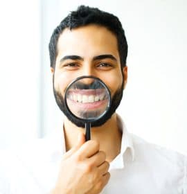 man holding magnifying glass to his smile