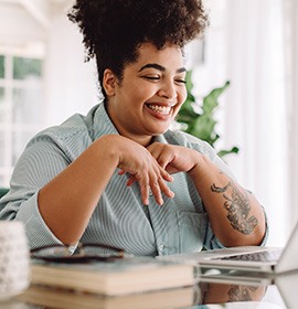 Woman smiling while working on laptop at home