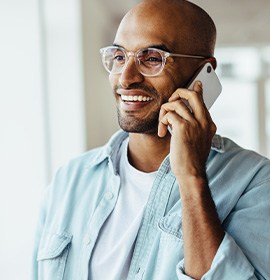 Man with glasses smiling while talking on phone