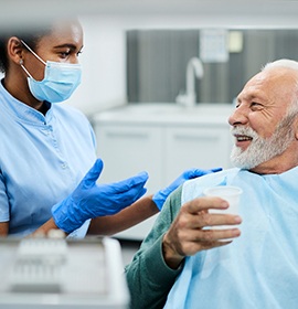 dental hygienist talking to older male patient 