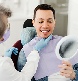 Man smiling at reflection in mirror with dentist