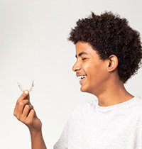 Profile view of teenager in gray t-shirt holding Invisalign