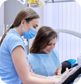 Dentist with mask showing tablet to patient