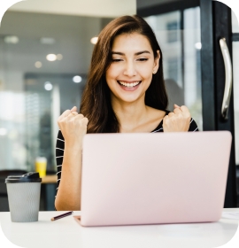 Smiling woman pumping fists while looking at laptop
