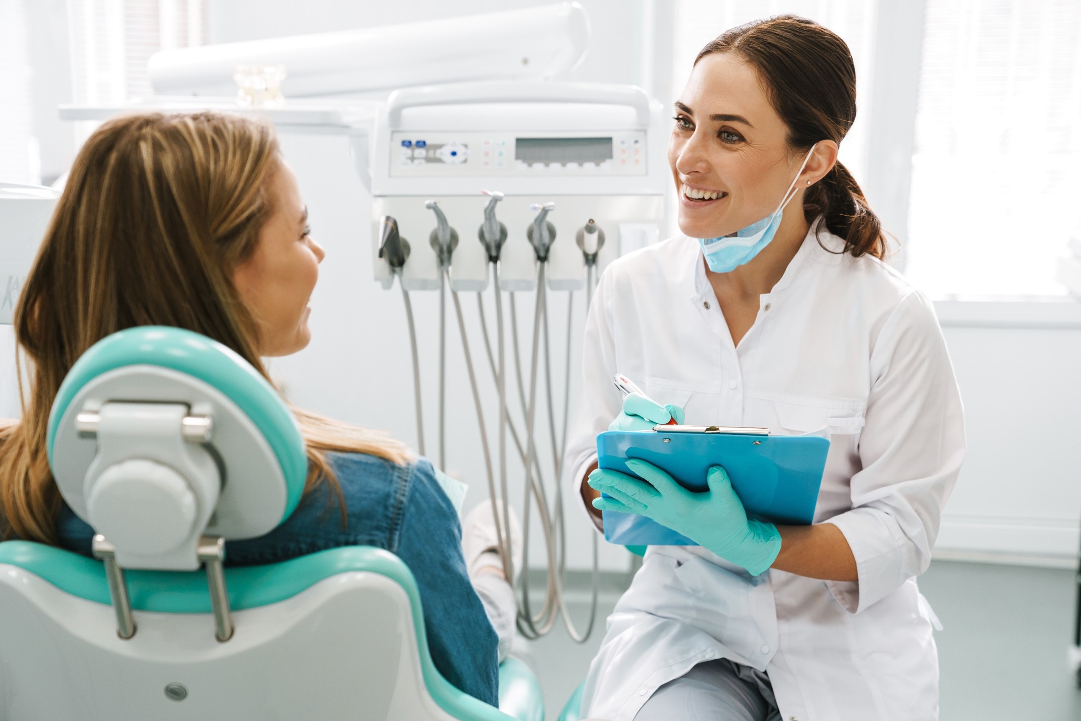 Dentist smiling at patient while taking notes on clipboard